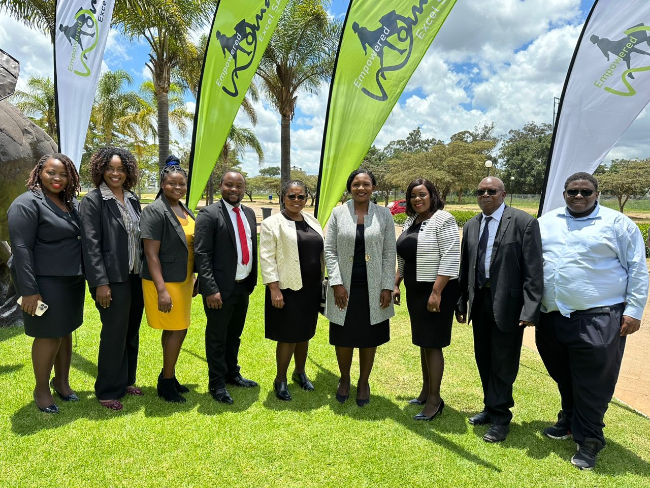 SACCO's staff standing on a lawn in front of backdrops