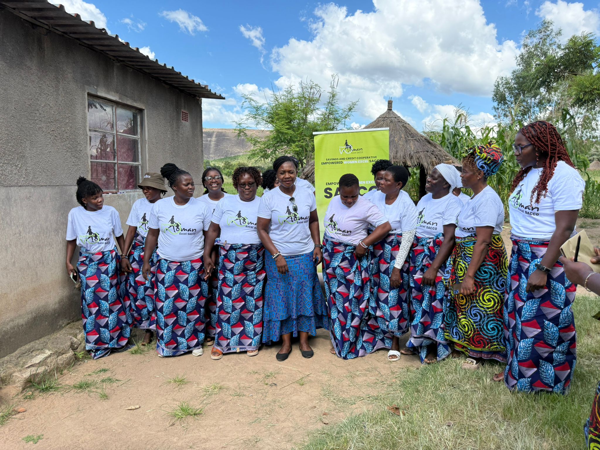 Women standing in a rural area with SACCO branded tshirts and chitenge cloths